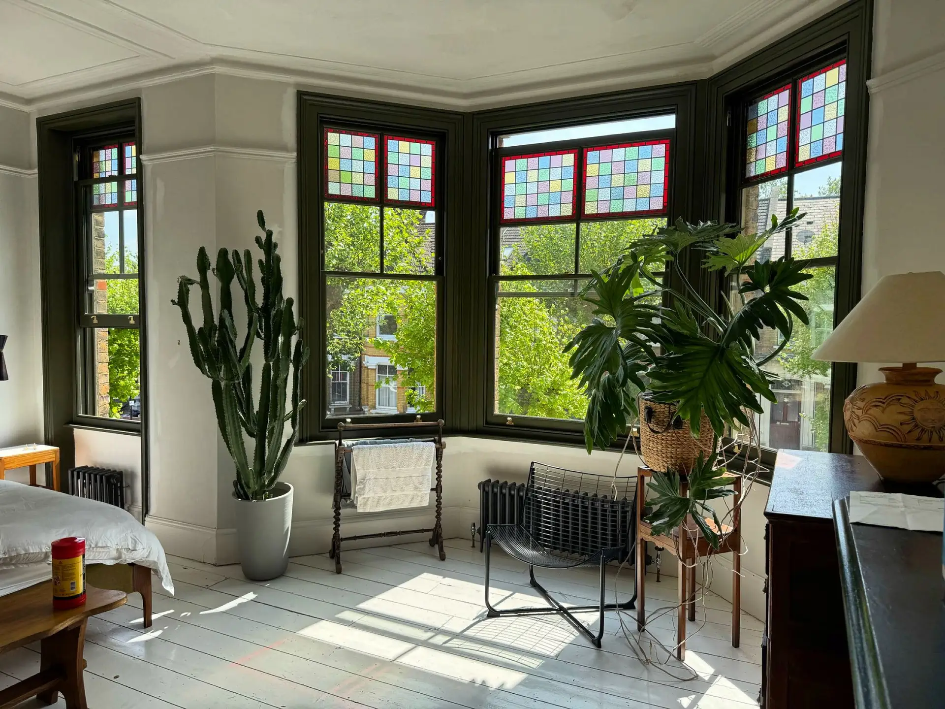 Interior view of a large dark-framed bay window with sash panes in a sunlit room